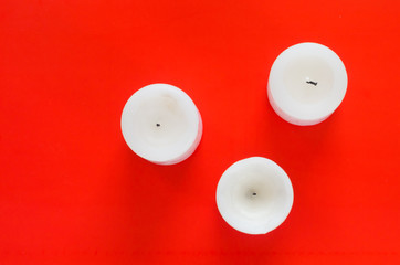 Three white candles on red background. Flat lay style template