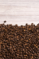 Roasted coffee beans in bulk on a light wooden background. dark cofee roasted grain flavor aroma cafe, natural coffe shop background, top view from above, copy space