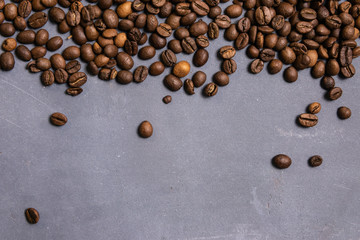 Roasted coffee beans in bulk on a gray concrete background. dark cofee roasted grain flavor aroma cafe, natural coffe shop background, top view from above, copy space
