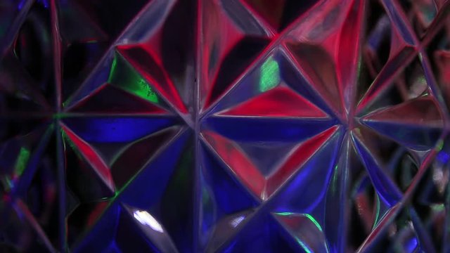 Against a background of triangles and rhombuses, the transfusion of light of multicolored rays