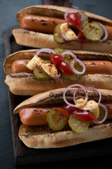 Hot-dogs with grilled sausages, pickles, red onion and sauces, close-up, vertical shot