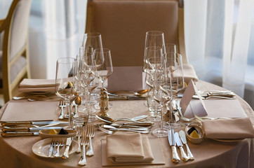 Wooden table served with plates, forks, spoons, glasses, napkins in the restaurant