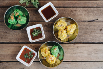 Chinese dim sum in plates at wooden background