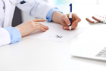 Female doctor filling up prescription form while sitting at the desk in hospital closeup.  Healthcare, insurance and excellent service in medicine concept 