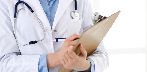 Female doctor using medical form on clipboard closeup.  Physicianat work in hospital or clinic. Healthcare, insurance and medicine concept 