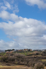 Fototapeta na wymiar Blue cloudy sky on a green Tuscany rural landscape in San Gimignano