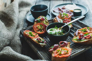 rustic breakfast, baked with basil, tomato, salami and cheese slices of bread, fried egg and bacon