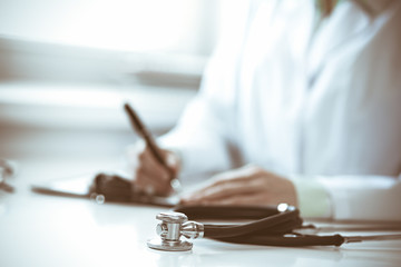Stethoscope at doctor workplace desk. Physician woman working with medication history records form in clinic. Medicine and health care concept. Green is main color