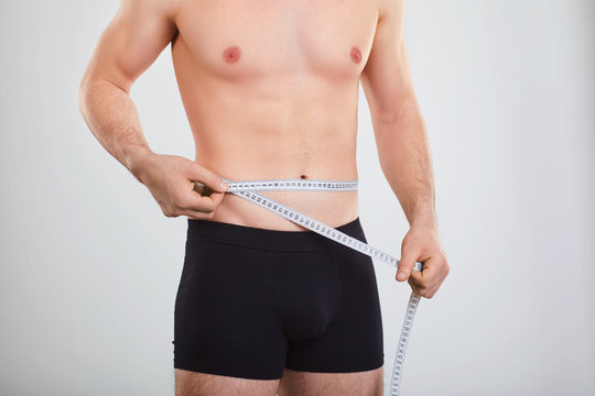 A man in underwear measures the waist with a centimeter