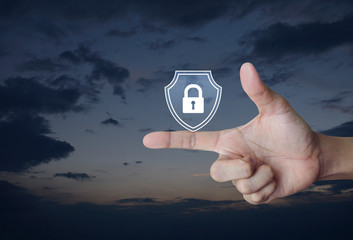 Hand pressing padlock with shield flat icon over sunset sky, Business security insurance concept