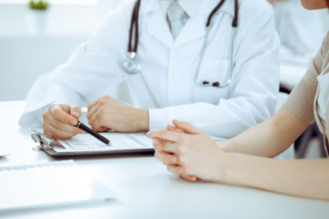 Doctor man and patient are discussing something, just hands at the table. Medicine and health care concepts