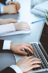 Group of business people working together in office. Man hands typing on laptop computer