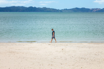 Fototapeta na wymiar man walking alone at the beach New Zealand
