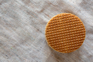 Stack of sweet homemade Dutch stroopwafels with honey-caramel filling on cloth, top view. Copy space.