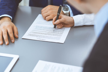 Group of business people and lawyer discussing contract papers sitting at the table, closeup. Businessman is signing document after agreement done