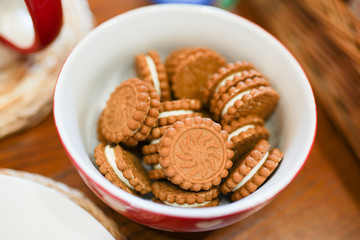 Biscuit sweet cookie with white icing background on white and red plate on brown wooden table . tasty food for tea