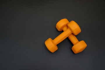 two orange dumbbells isolated on black background