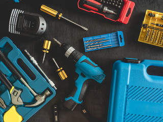 top view of Construction tools concept with Drill sets, hammer, screwdriver and Toolbox on black wooden background.