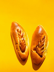 Two freshly home baked artisan Easter stuffed bread loafs cakes decorated with pastry ornament on bright yellow background. Trendy style with harsh light hard shadows. Holiday baking concept