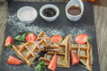 Homemade square Belgian waffles with ricotta cheese, chocolate, strawberries and cherries for breakfast. View from above