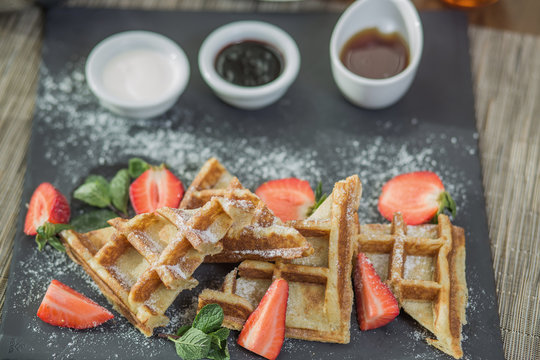 Homemade square Belgian waffles with ricotta cheese, chocolate, strawberries and cherries for breakfast. View from above