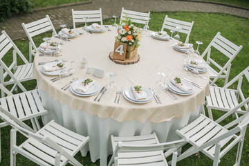 Wedding. Banquet. Chairs and a round table for guests decorated with candles served as cutlery and crockery and covered with a tablecloth