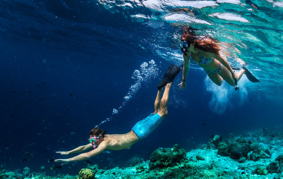 Young couple snorkeling and do skin diving on the coral reef edge in tropical waters of the Maldives