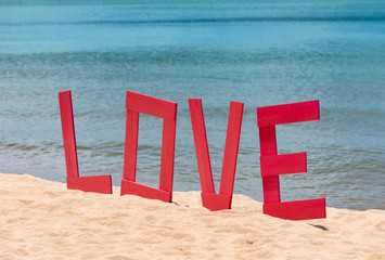 design of letters Love on the beach. The concept of loves and travel. Big letters Love on the sandy beach and on the sea background