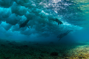 Underwater photographer takes photo of the female surfer diving under the wave