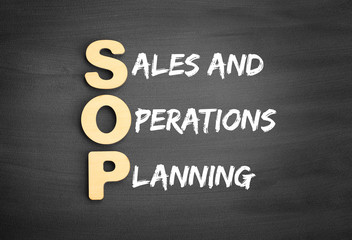 Wooden alphabets building the word SOP - Sales and Operations Planning acronym on blackboard