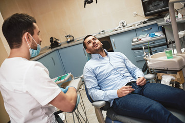 Make your dream smile a reality! Dentist in mask and latex gloves sitting near his patient in dental clinic