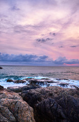 Waves crashing against rocks at sunset