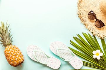 Travel flat lay items: fresh pineapple, sunglasses, beach slippers, tropical flower and palm leaf. Place for text. Top view. Summer concept