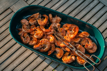 Ceramic dish with spicy grilled shrimps closeup on wooden rustic table background