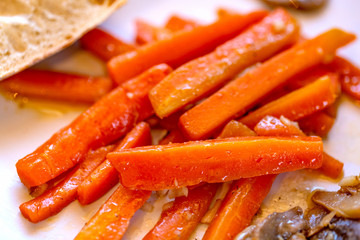 Carrots with mushrooms and garlic. Large juicy slices of sauteed vegetables on a plate. Cooked sliced carrots and mushrooms. Vegetarian food. Soft focus. Top view.