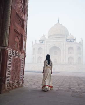woman with white long dress in Taj Mahal in foggy morning