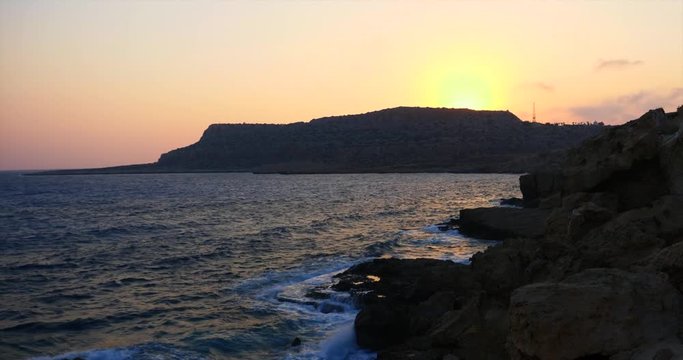 Beautiful landscape from the shore at sunset in Cyprus. Amazing landscape with sea, waves, and mountains in the background