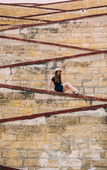 Young girl sitting on the city walls, old city of the Threee Cities