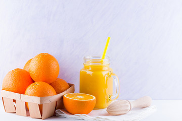 Orange fruits and juice on white background. Citrus fruit for making juice with manual juicer. Oranges in wooden box on white napkin. Mason jar with orange juice