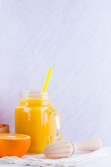 Orange fruits and juice on white background. Citrus fruit for making juice with manual juicer. Oranges in wooden box on white napkin. Mason jar with orange juice