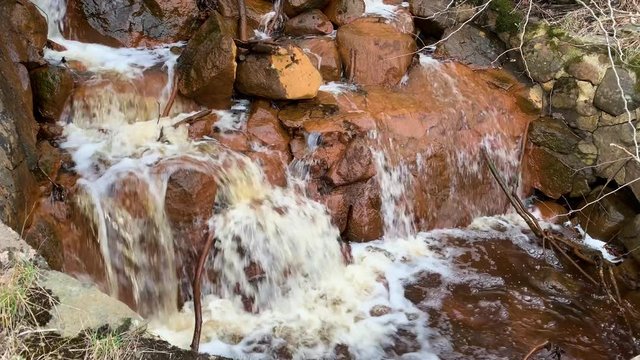 A little serene waterfall on orange rocks in Skatas, Gothenburg, Sweden