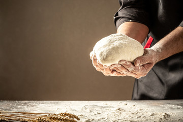 Man baking bread. Sprinkling some flour on dough. Hands kneading dough. Food concept. space for text