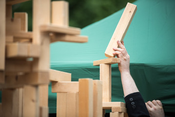 Person baut Turm aus Holz Bausteinen und balanciert das letzte Stück