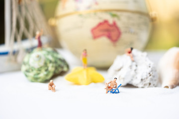 Miniature people, travelers relaxing on the sand box decorating in summer theme using as background travel, exploring the world, budget trip concept.