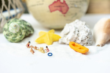 Fototapeta premium Miniature people, travelers relaxing on the sand box decorating in summer theme using as background travel, exploring the world, budget trip concept.