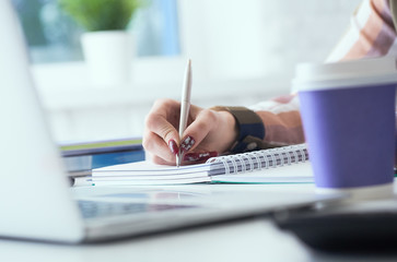 Businesswoman making notes with silver pen in office background. Just hands over the table. Business finance savings loan and credit concept.