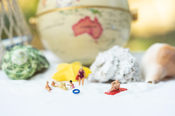 Miniature people, travelers relaxing on the sand box decorating in summer theme using as background travel, exploring the world, budget trip concept.