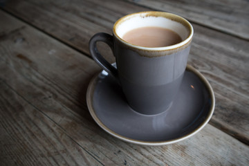 Cup of White Tea in earthen ware mug with matching saucer on wooden table.  Rustic shabby chic look