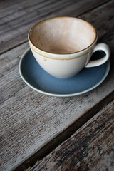 Empty cup of coffee in earthern ware cup with saucer on rustic wooden table