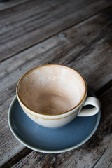 Empty cup of coffee in earthern ware cup with saucer on rustic wooden table